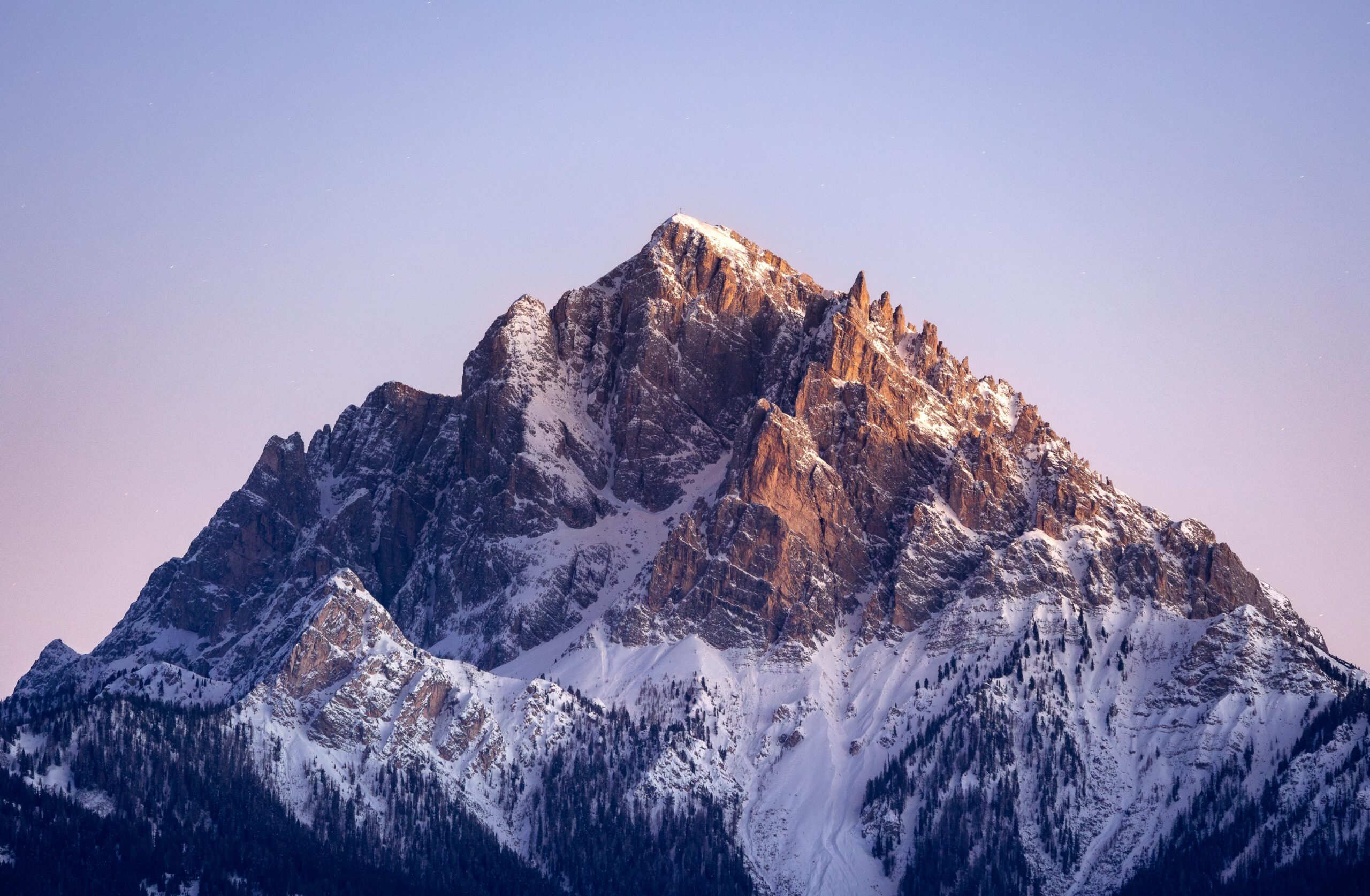 Breathtaking view of a snow-capped mountain peak in the Dolomites, Italy, at sunset.