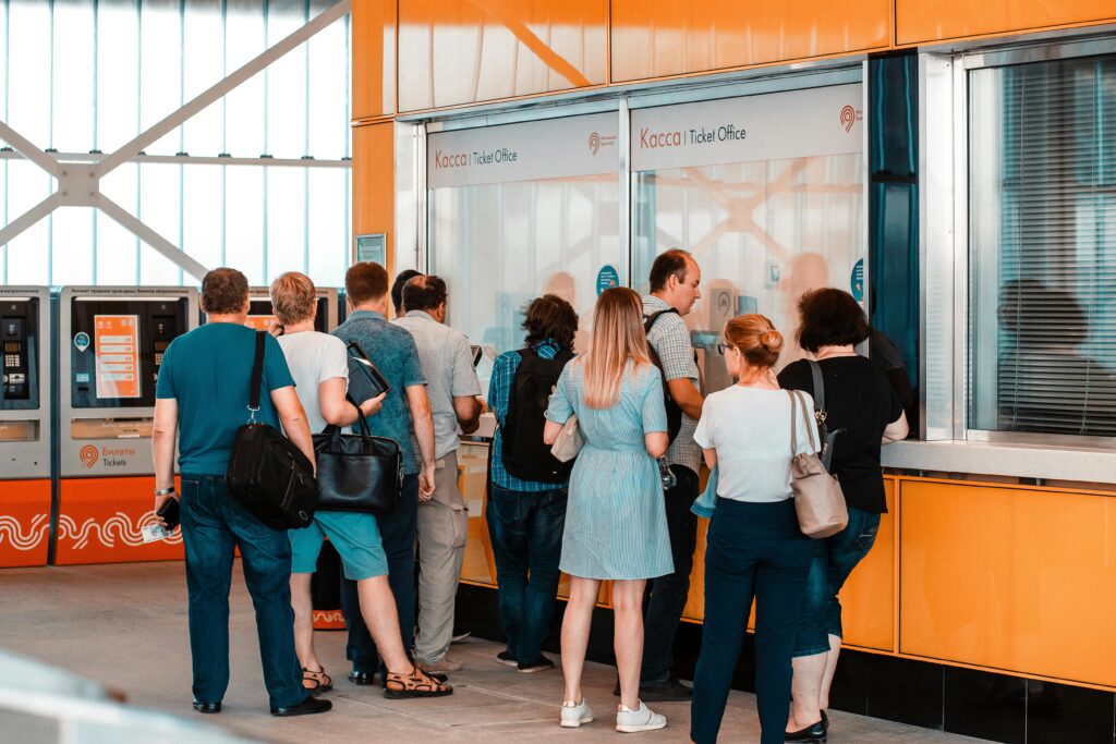 Back view of tourists at counter of a ticket office, probably waiting to be admitted to a visit