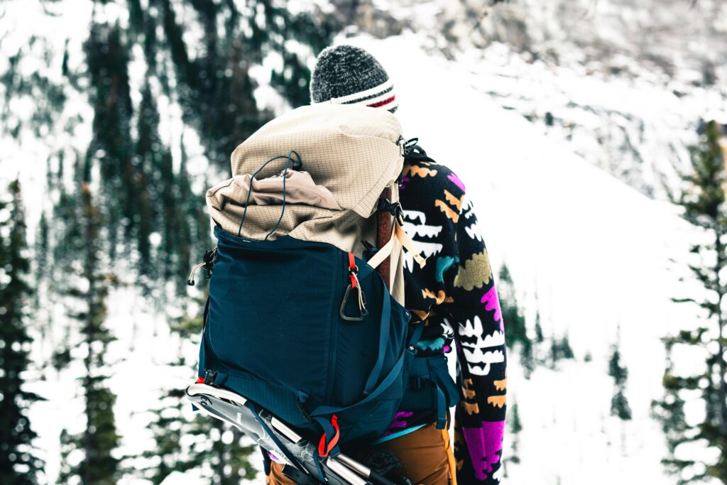 A hiker wearing a colorful jacket explores a snowy mountain in Glacier, Canada.
