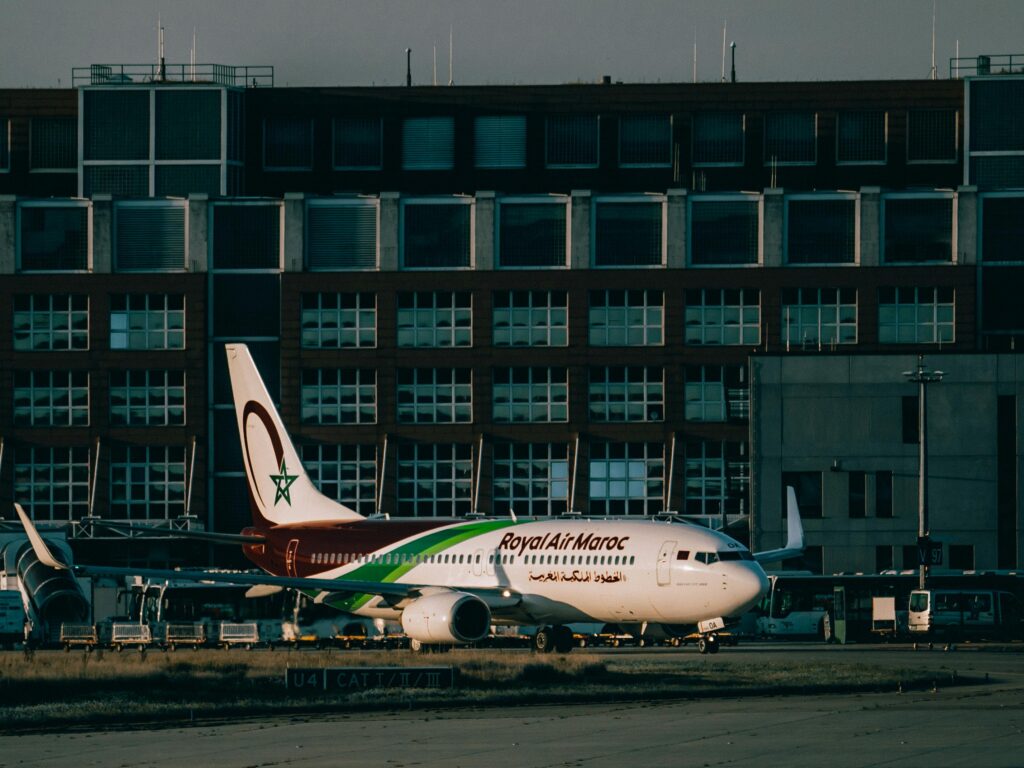 Royal Air Maroc aircraft parked at an airport apron with terminal building in the background.