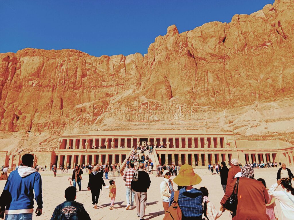 Crowds visiting the iconic Mortuary Temple of Hatshepsut, Luxor, Egypt under a clear blue sky.