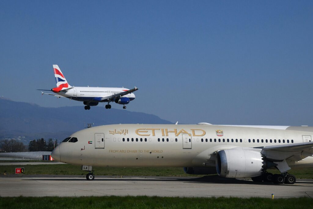 A British Airways and Etihad airplane at Geneva Airport on a clear day.