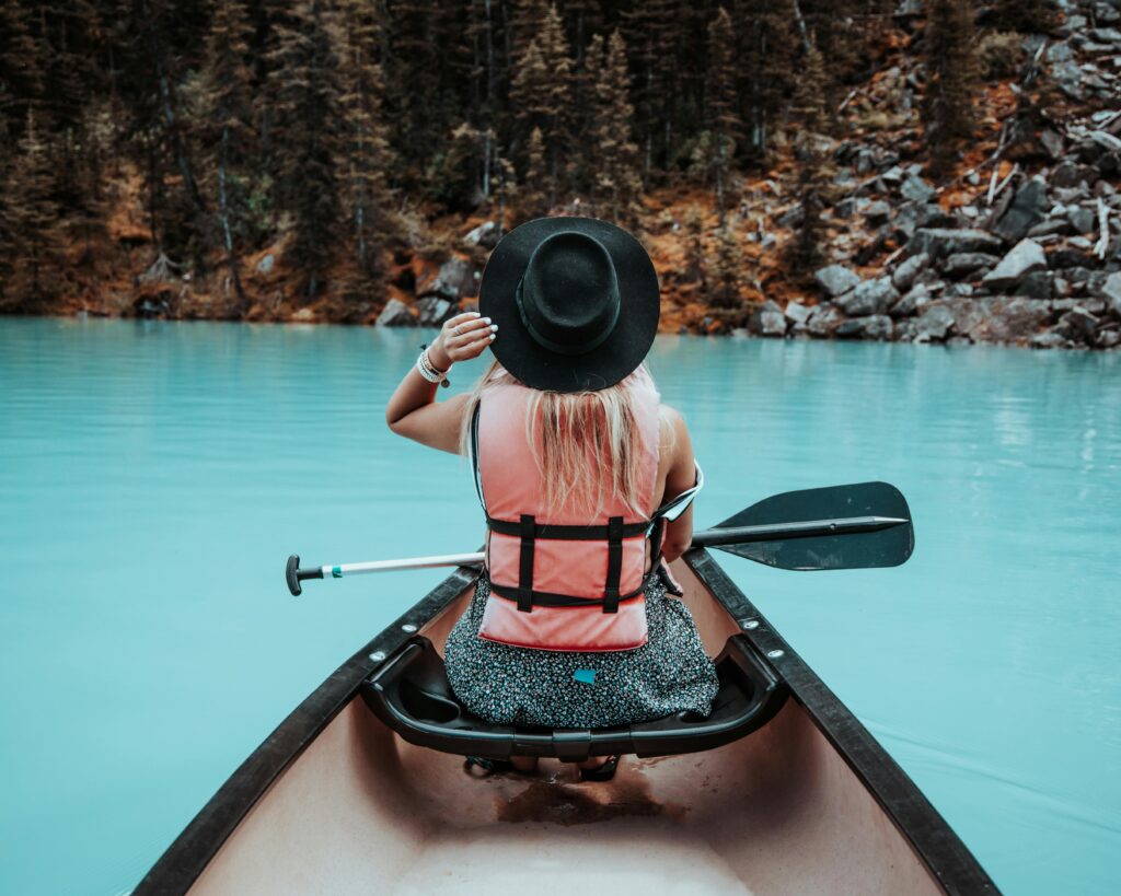 Back view of a woman kayaking on turquoise waters at Lake Louise, Canada, in summer, best lakes in North America.